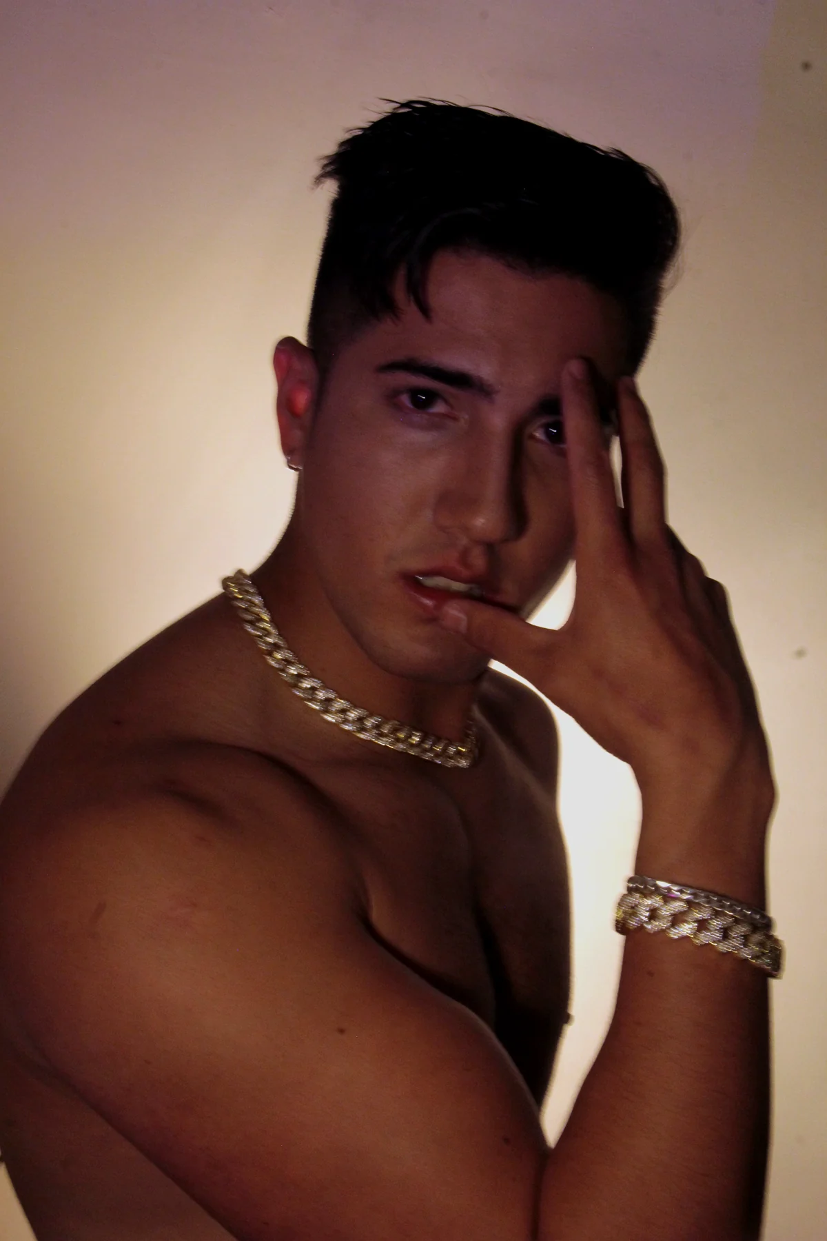 FRANKOWW en retrato dorado con joyería y manos sobre el rostro